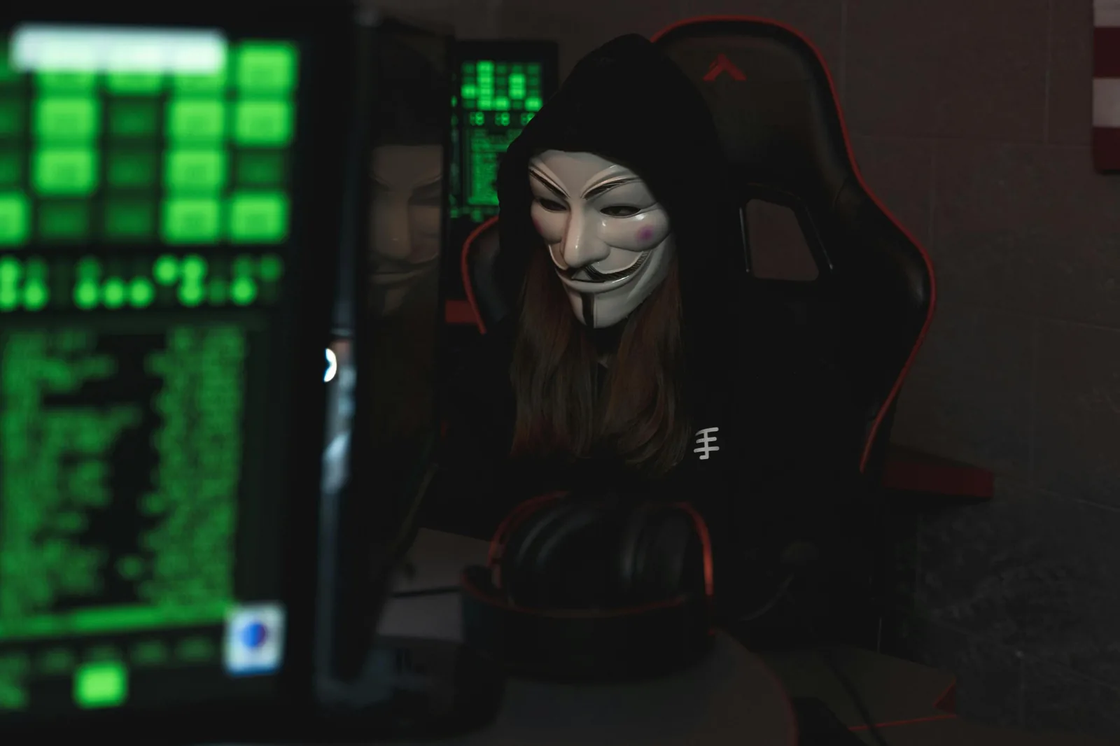 Masked cybercriminal at computer representing AI used as offensive weapon for phishing and deepfake fraud