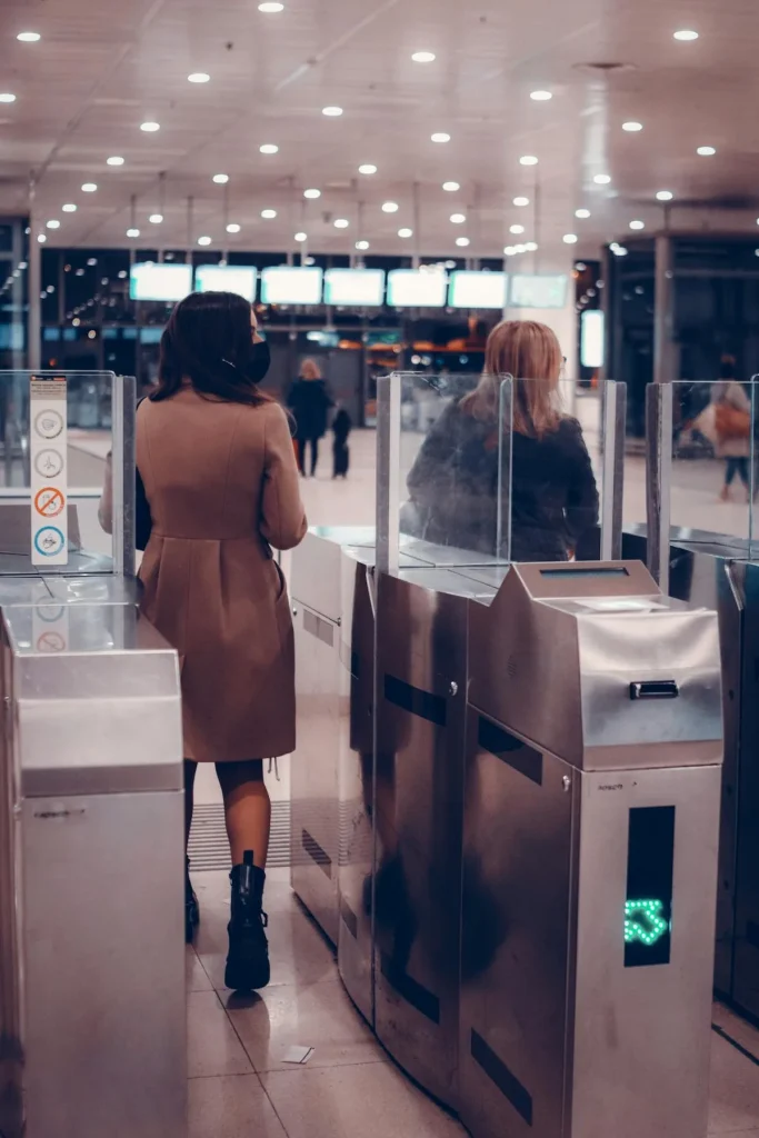 Two passengers at automated airport security gates with biometric AI verification technology
