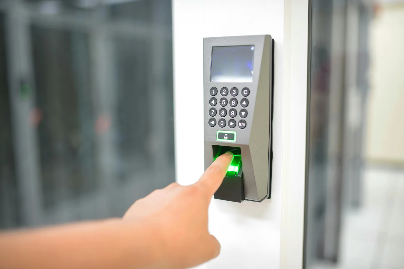Person using fingerprint scanner biometric authentication device for AI-driven access control in professional building