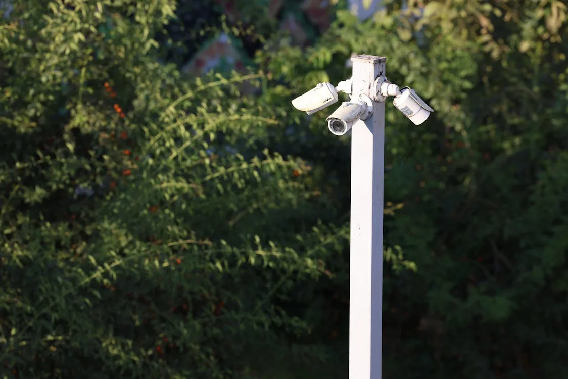 Cluster of outdoor surveillance cameras mounted on a pole in a school campus environment representing AI-powered physical security monitoring systems