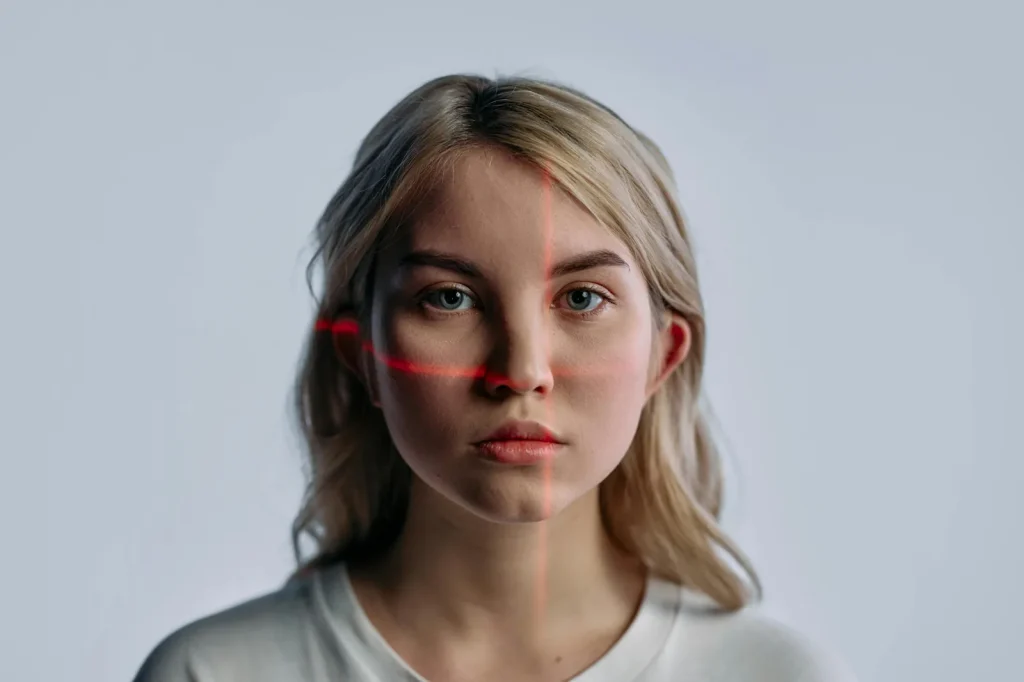 Woman with red laser facial recognition scanning lines representing AI deepfake and identity security risks