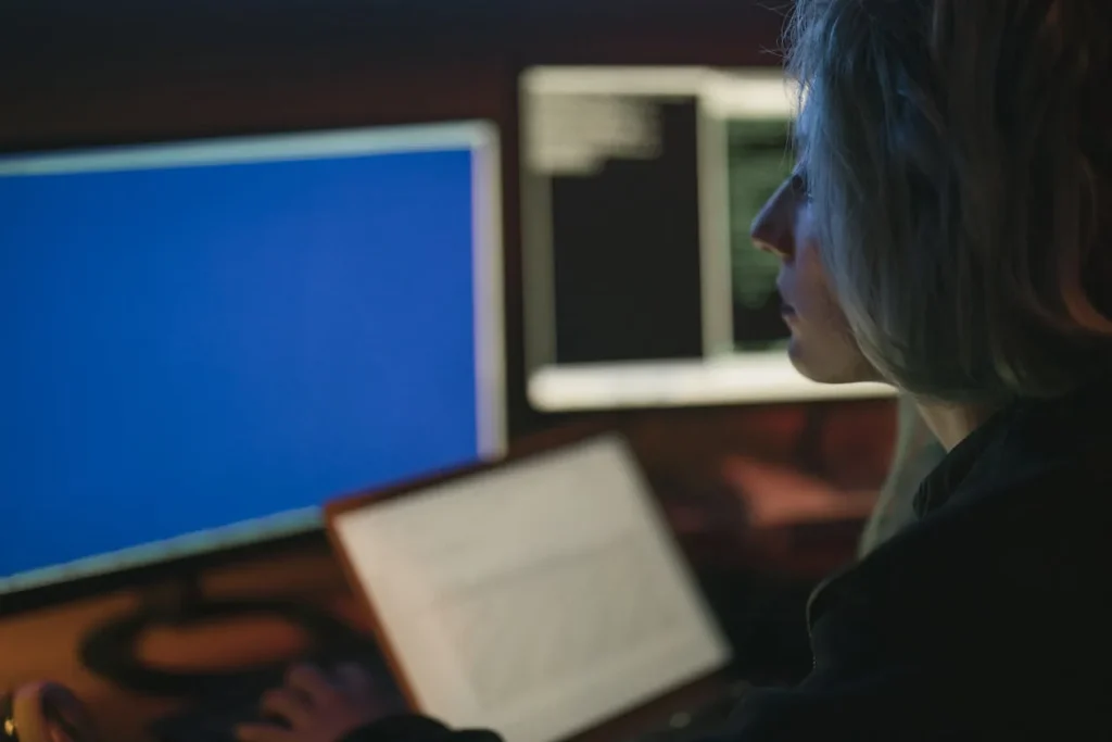 Cyber security intelligence analyst monitoring multiple screens in dark environment