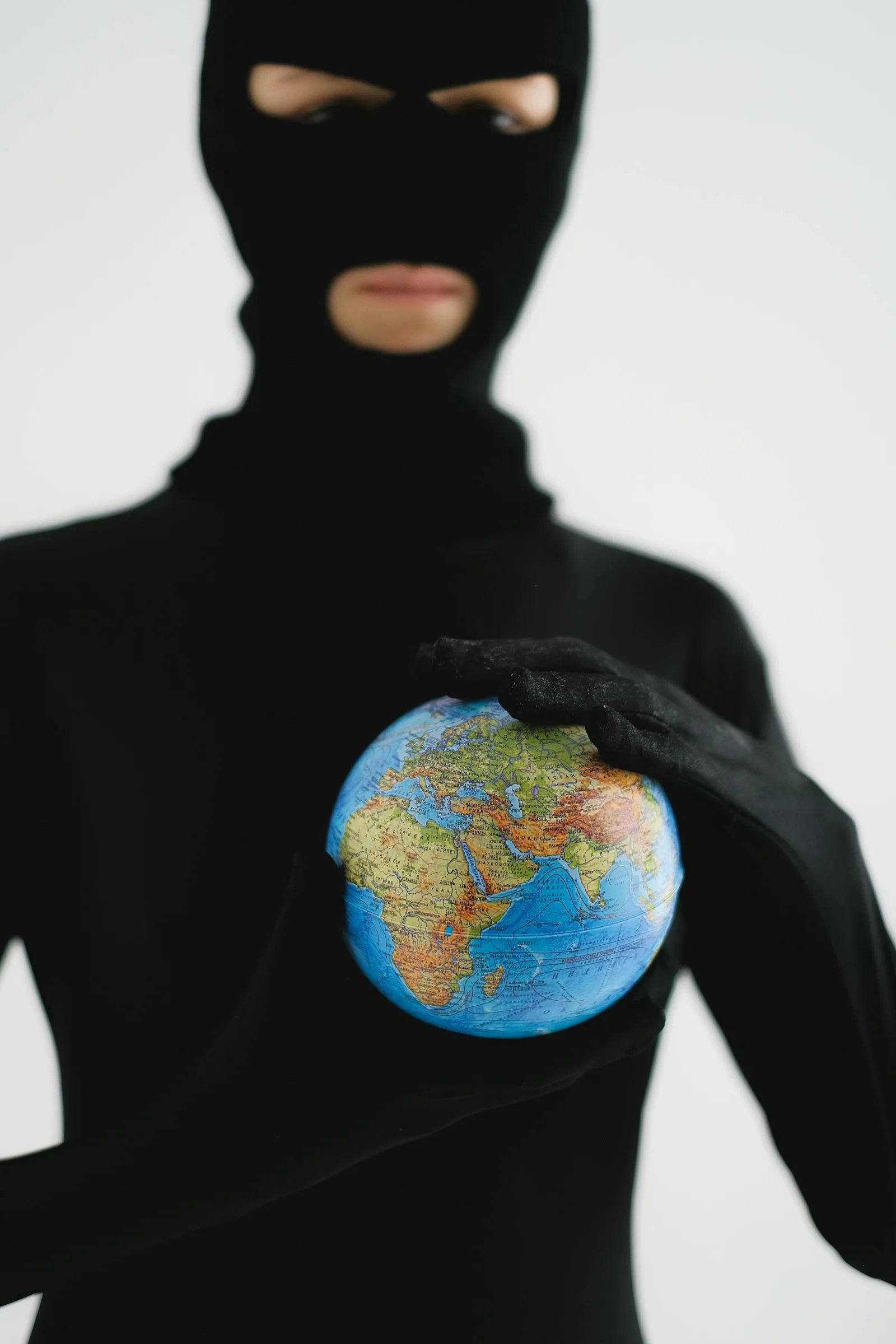 Masked figure holding globe representing global threat landscape monitored by security intelligence analysts