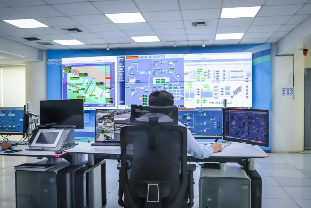 Operator monitoring industrial control systems on SCADA screens in a modern control room