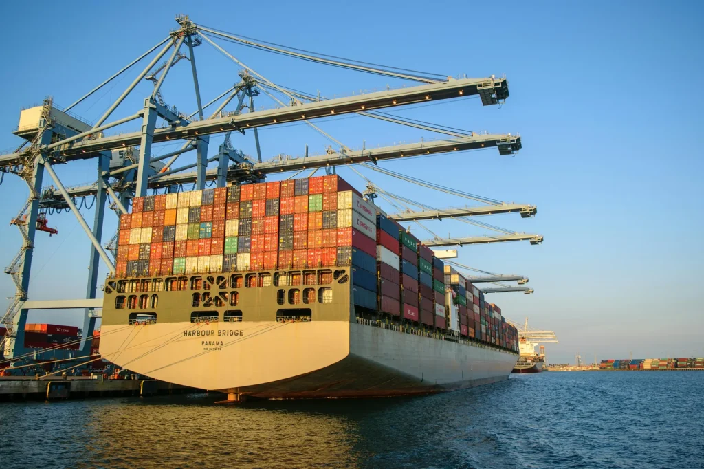 Large container ship at port with cargo cranes representing maritime security intelligence threats shipping disruption global trade