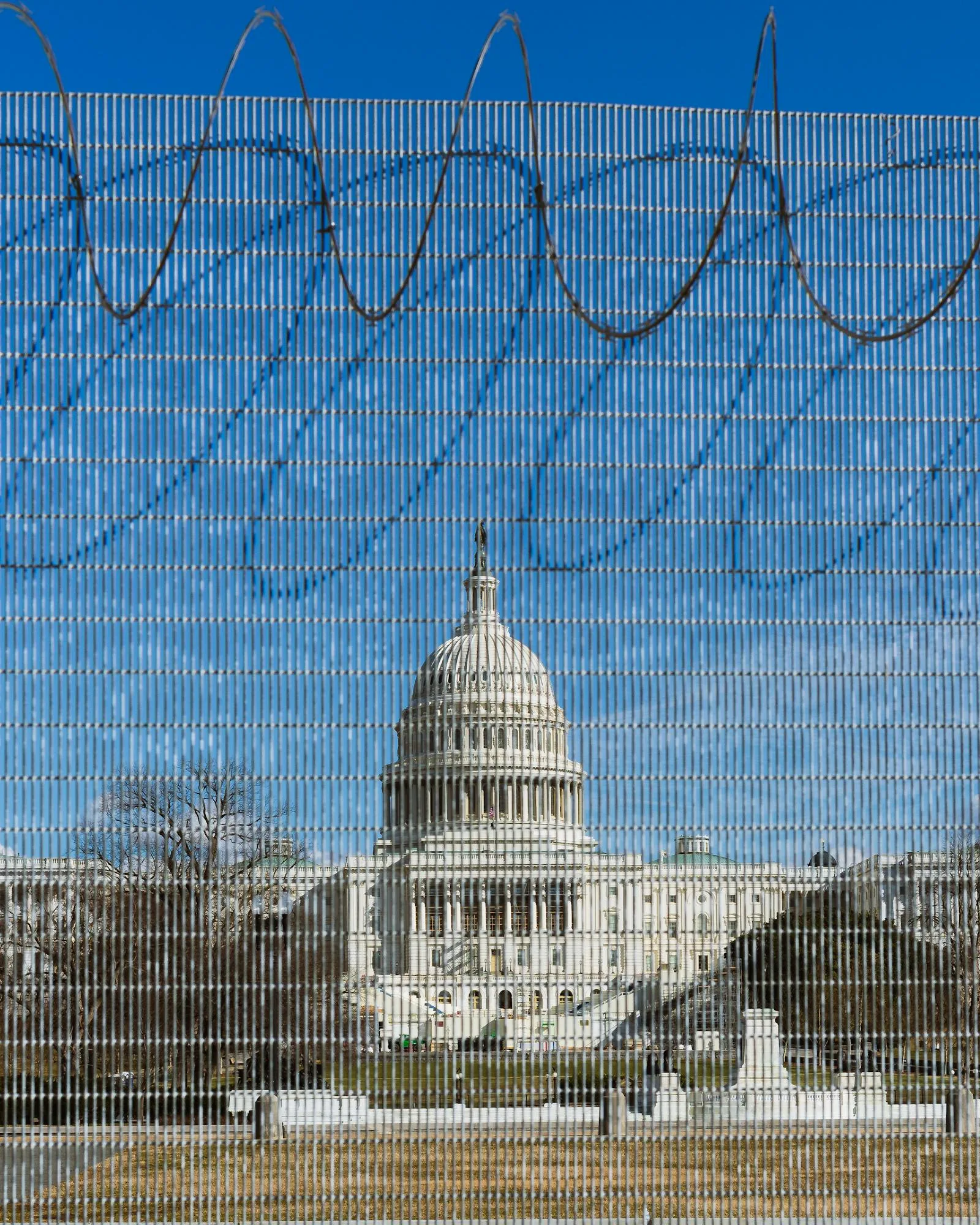 US Capitol Building visible behind a security perimeter fence with razor wire representing national security and intelligence community careers