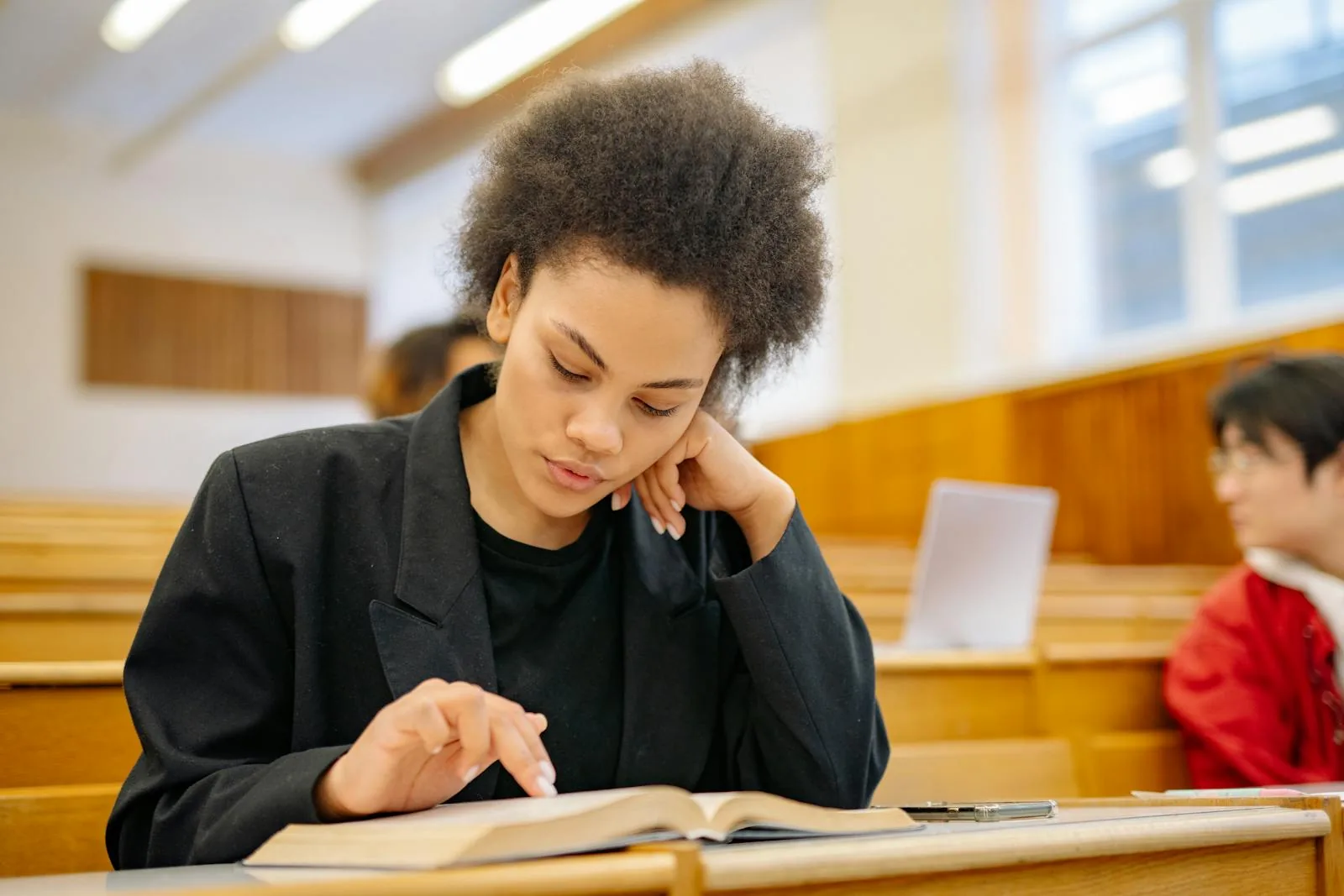 Young woman reading a book with concentration in university lecture hall representing intelligence and security studies curriculum
