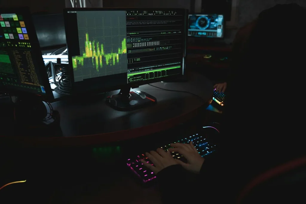 Cybersecurity expert typing on RGB keyboard with multiple monitors displaying security analytics and threat data