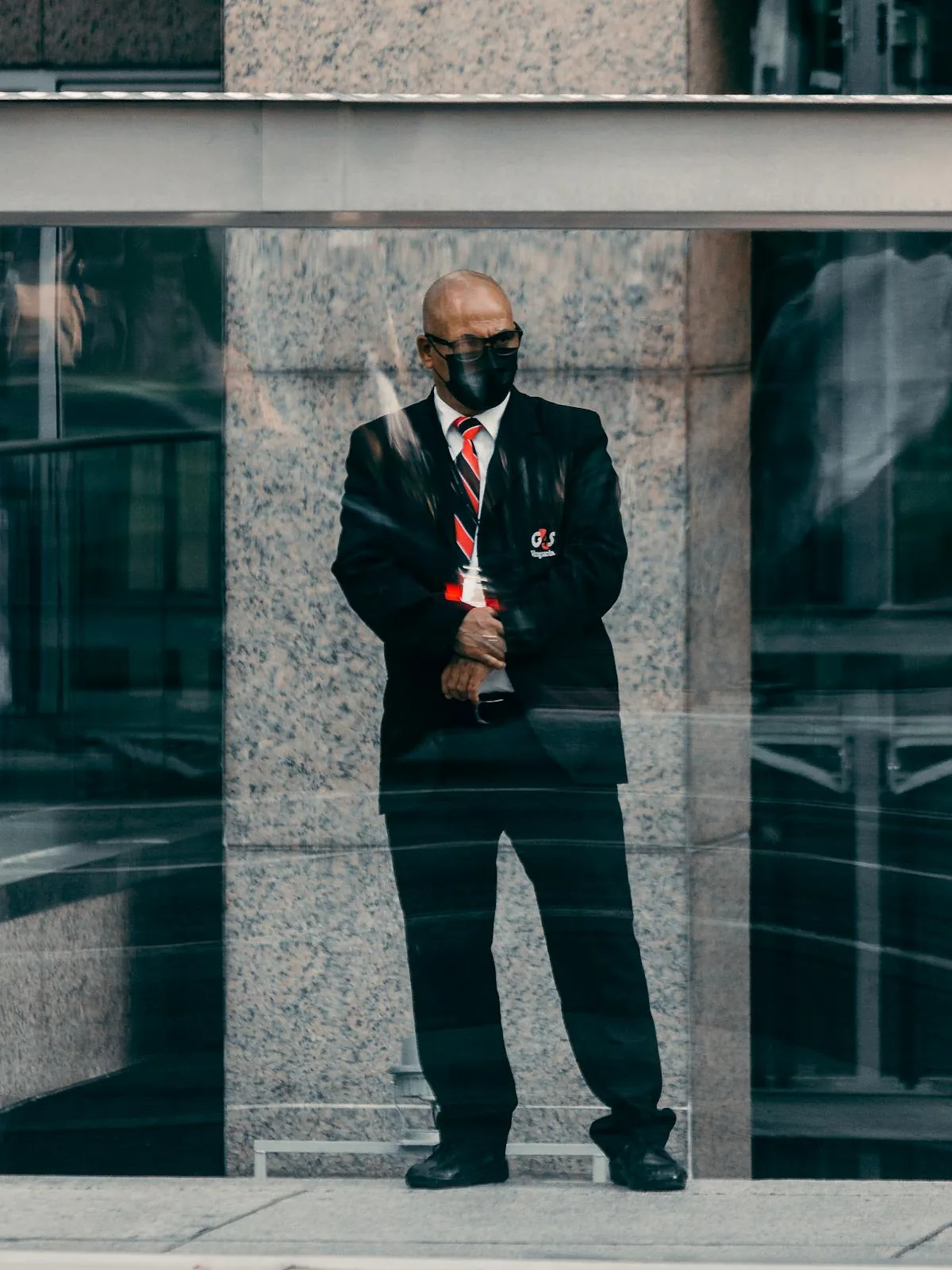 Security guard in suit at corporate building entrance representing physical security intelligence services