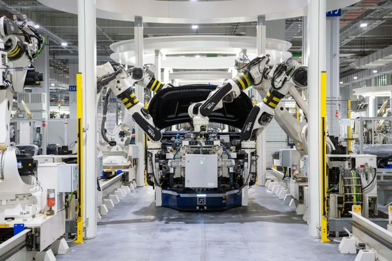 Industrial robot arms assembling vehicle in modern manufacturing facility representing robotics artificial intelligence and cyber security enterprise attack surface