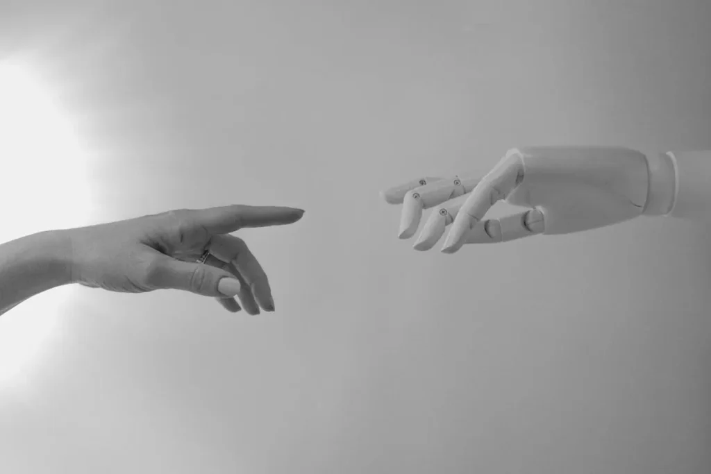Human and robot hands reaching toward each other representing the role of artificial intelligence in cyber security