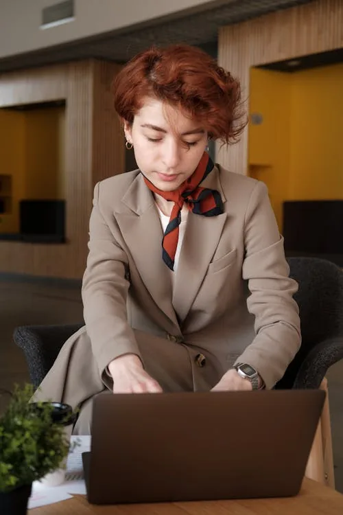 Security and intelligence studies graduate reviewing career development options on laptop in bright university office representing security intelligence studies careers applied cybersecurity