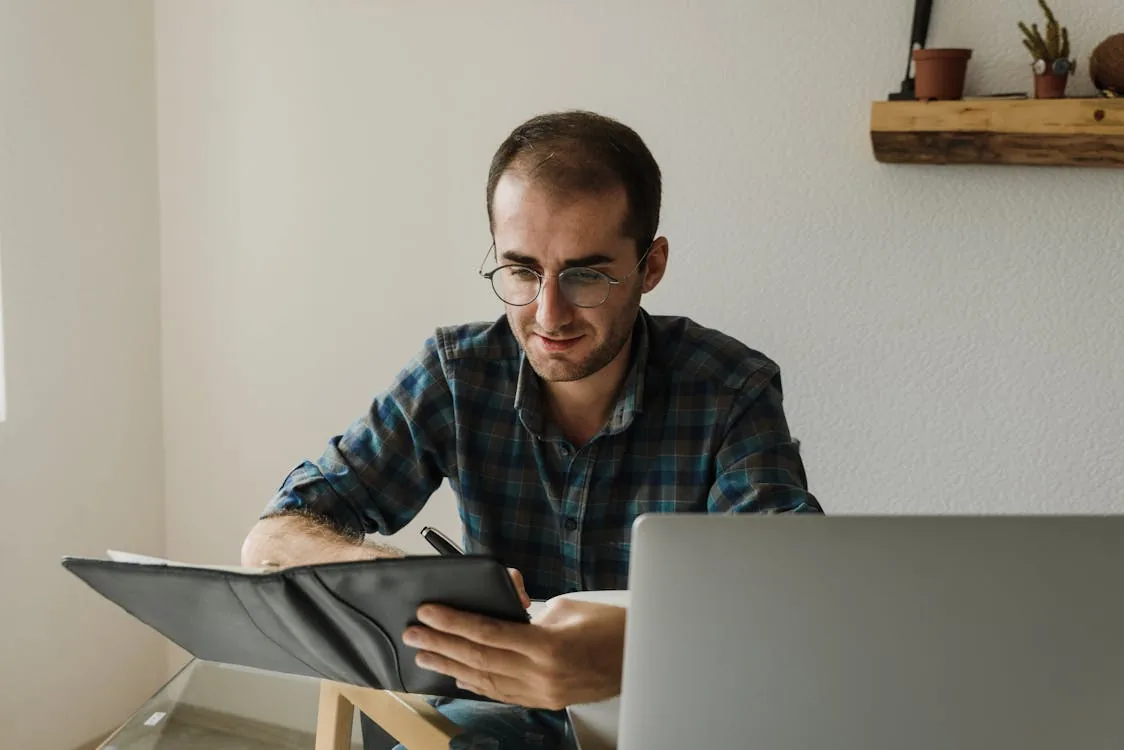Security intelligence analyst studying for professional certification on laptop in bright home office representing security intelligence analyst certifications career development SANS GIAC GCTI