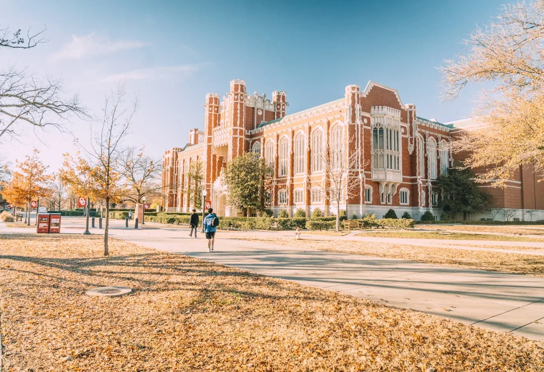 University of Oklahoma Gothic campus building with students walking in autumn for security and intelligence undergraduate programs