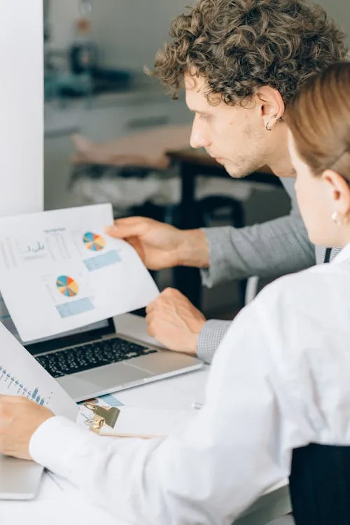 Two security professionals reviewing AI threat intelligence charts and data reports in bright office representing AI-driven security intelligence operations automation