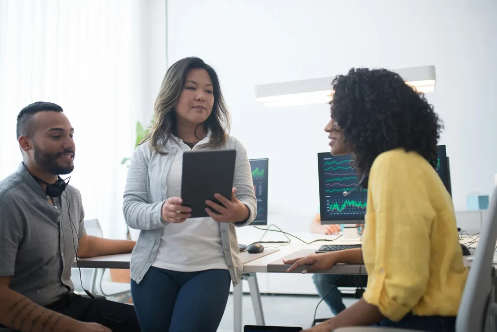 Diverse security operations team reviewing analytics dashboards in bright white modern office representing security intelligence operations SOC detection and response