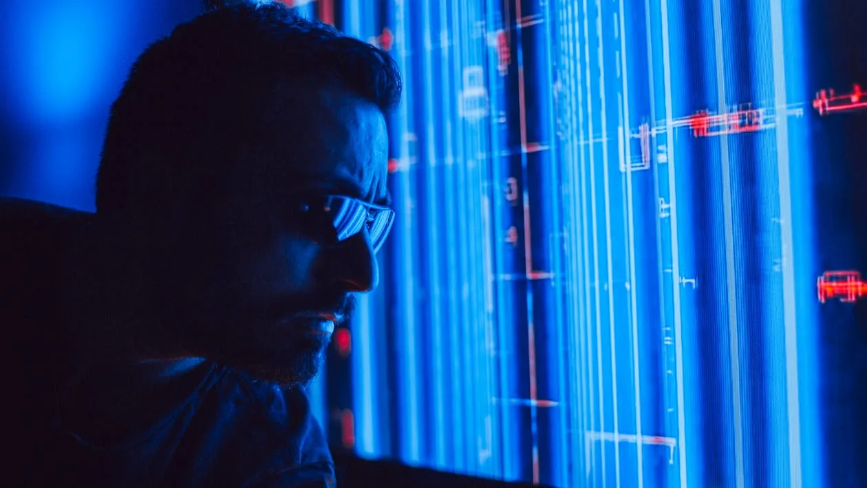 Security analyst with glasses studying blue holographic system architecture display representing how a security intelligence platform correlates and analyzes threat data