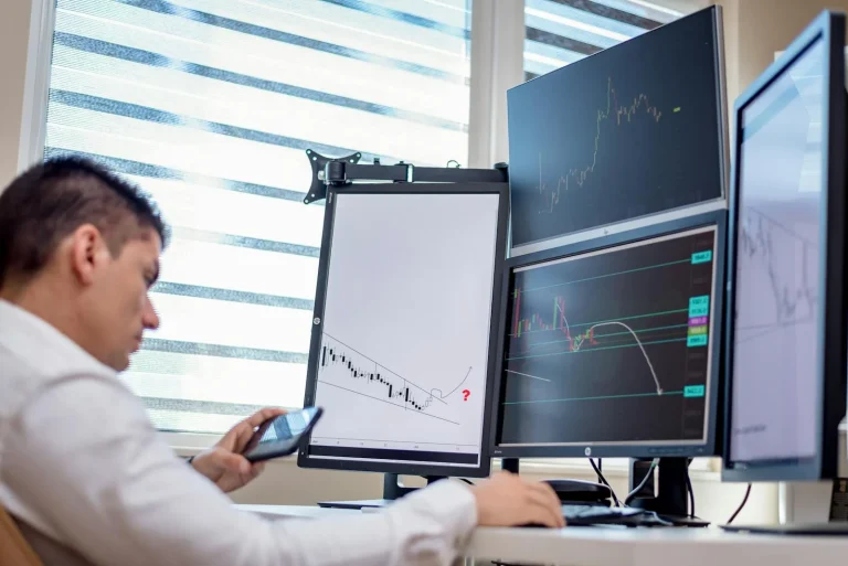 Analyst at multiple screens reviewing threat intelligence security market data and growth metrics