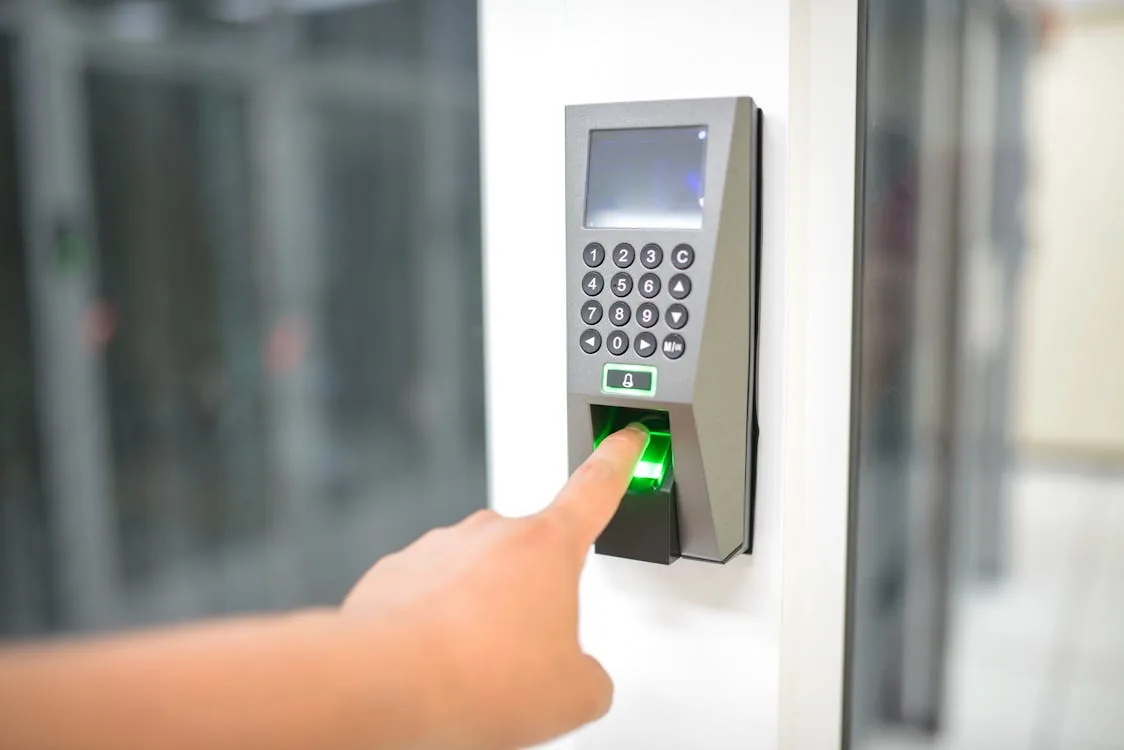 Finger pressing biometric fingerprint scanner with keypad on office building entry door for AI identity verification